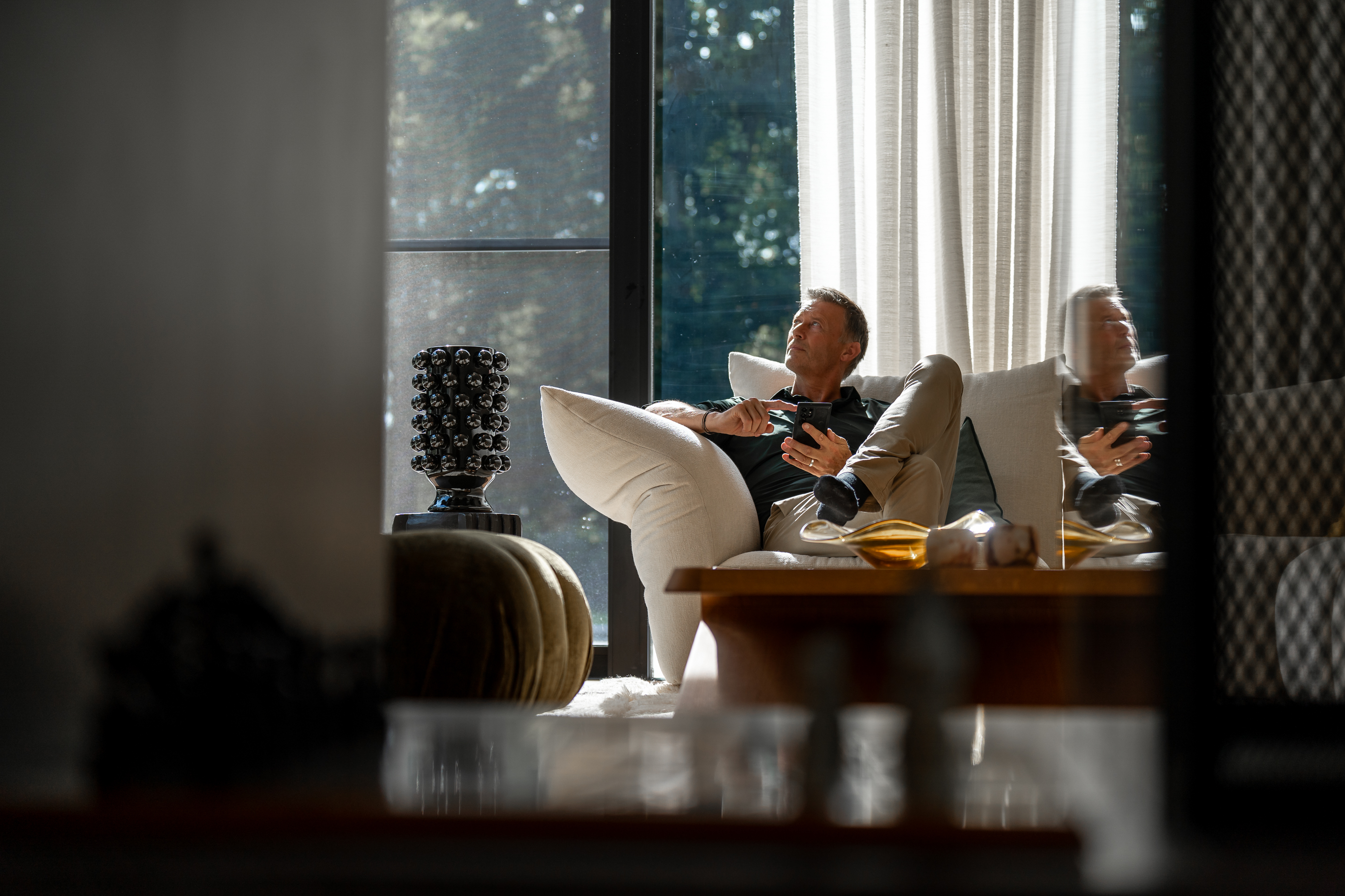 From his couch, a man uses his easy-to-use home automation system.