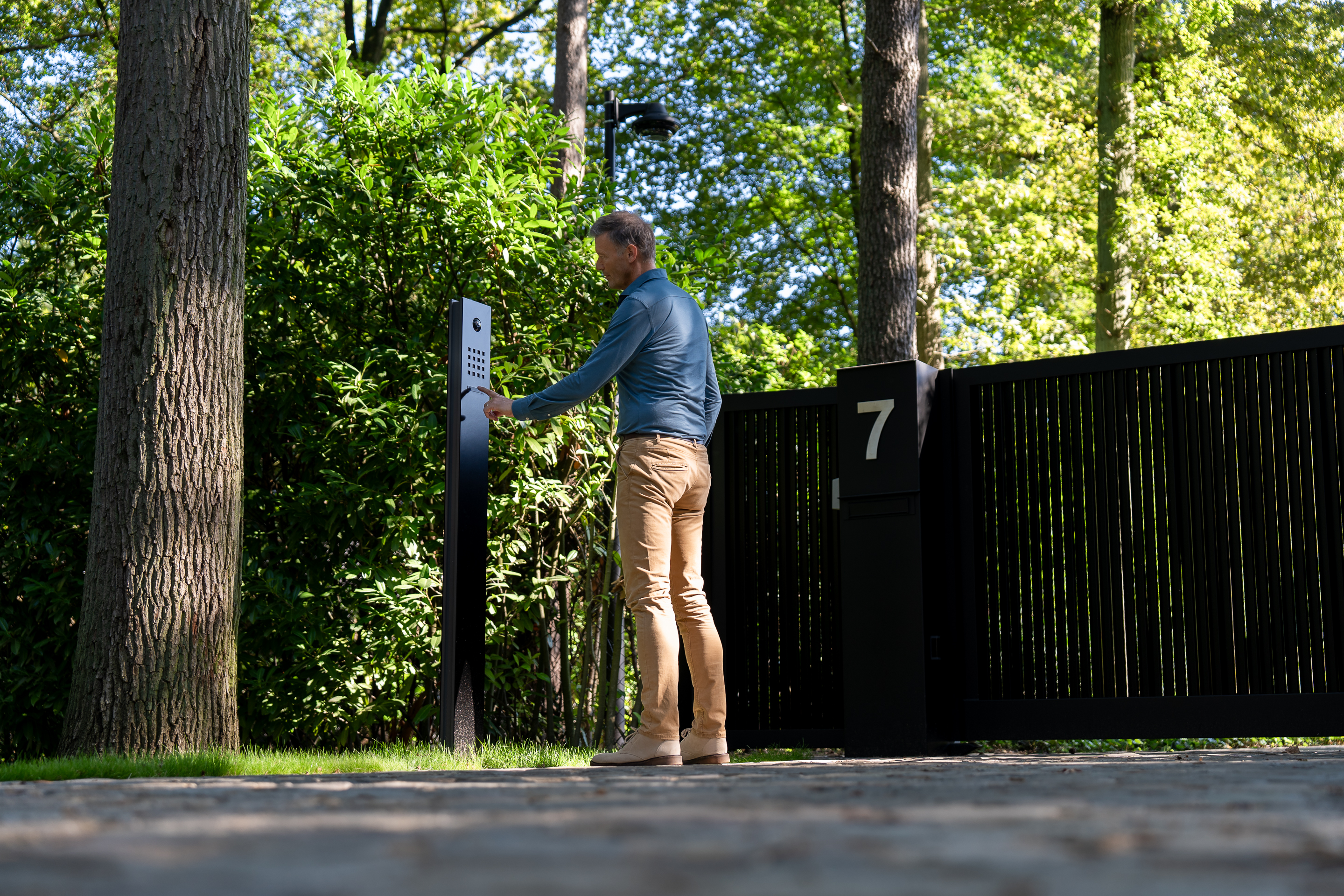 A man uses the integrated access system in front of his gate to enter his home.